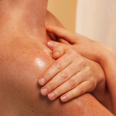woman rubbing body oil on shoulder
