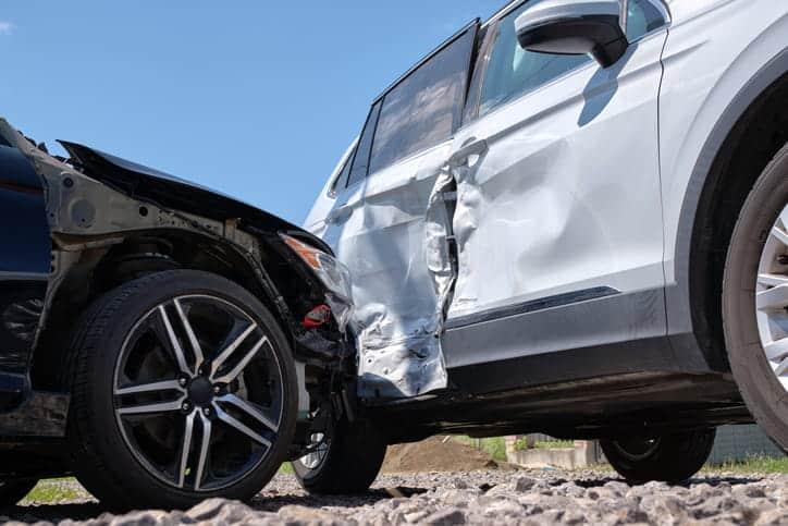 an up-close focus on the damage sustained to a white vehicle door after a black vehicle hit it. The black vehicle