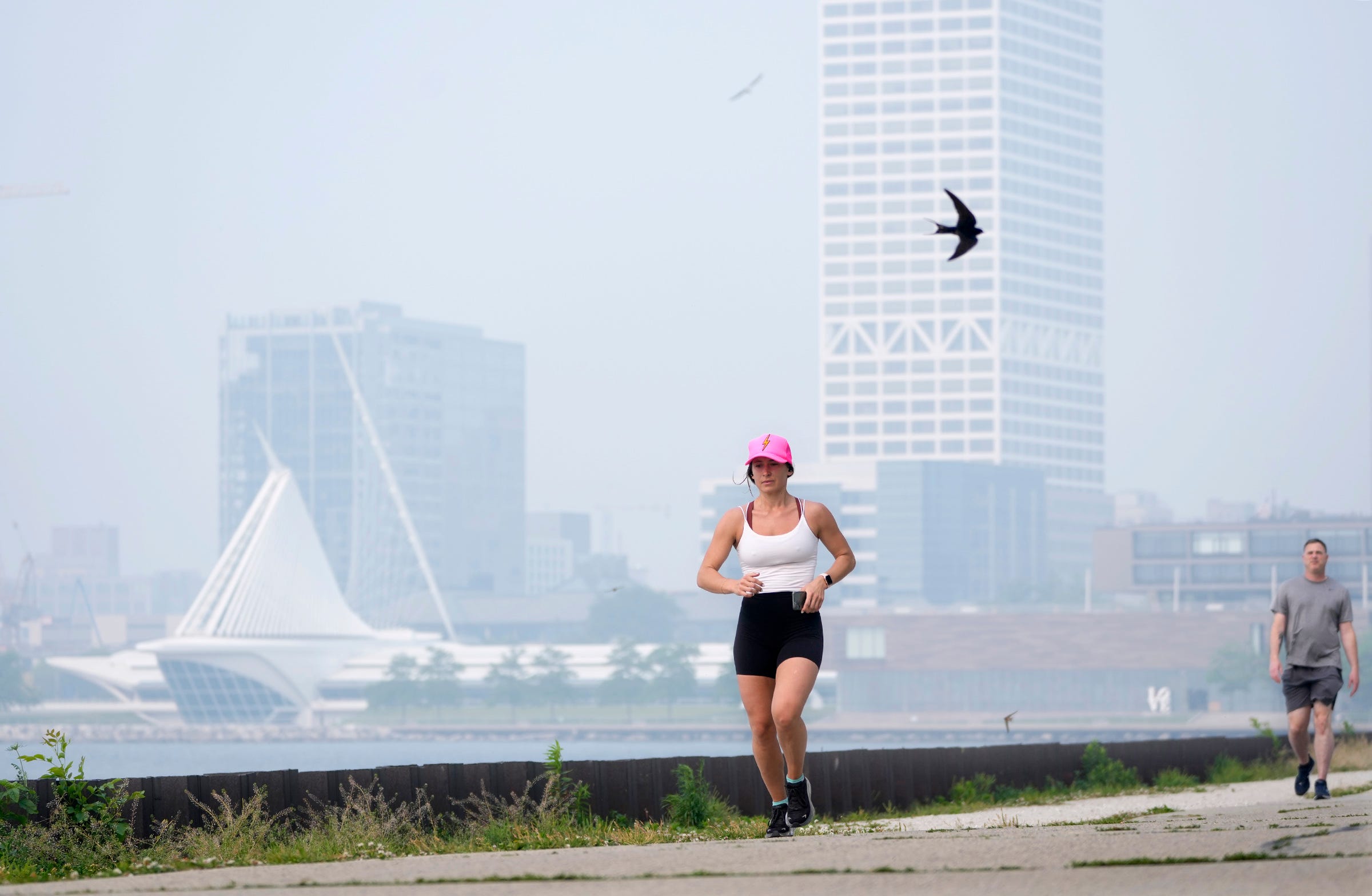 A haze of smoke hovers in the air as Alli Maddelein, of Milwaukee, takes a 5 mile jog through Veteran’s Park in Milwaukee on Tuesday. The quality of Wisconsin