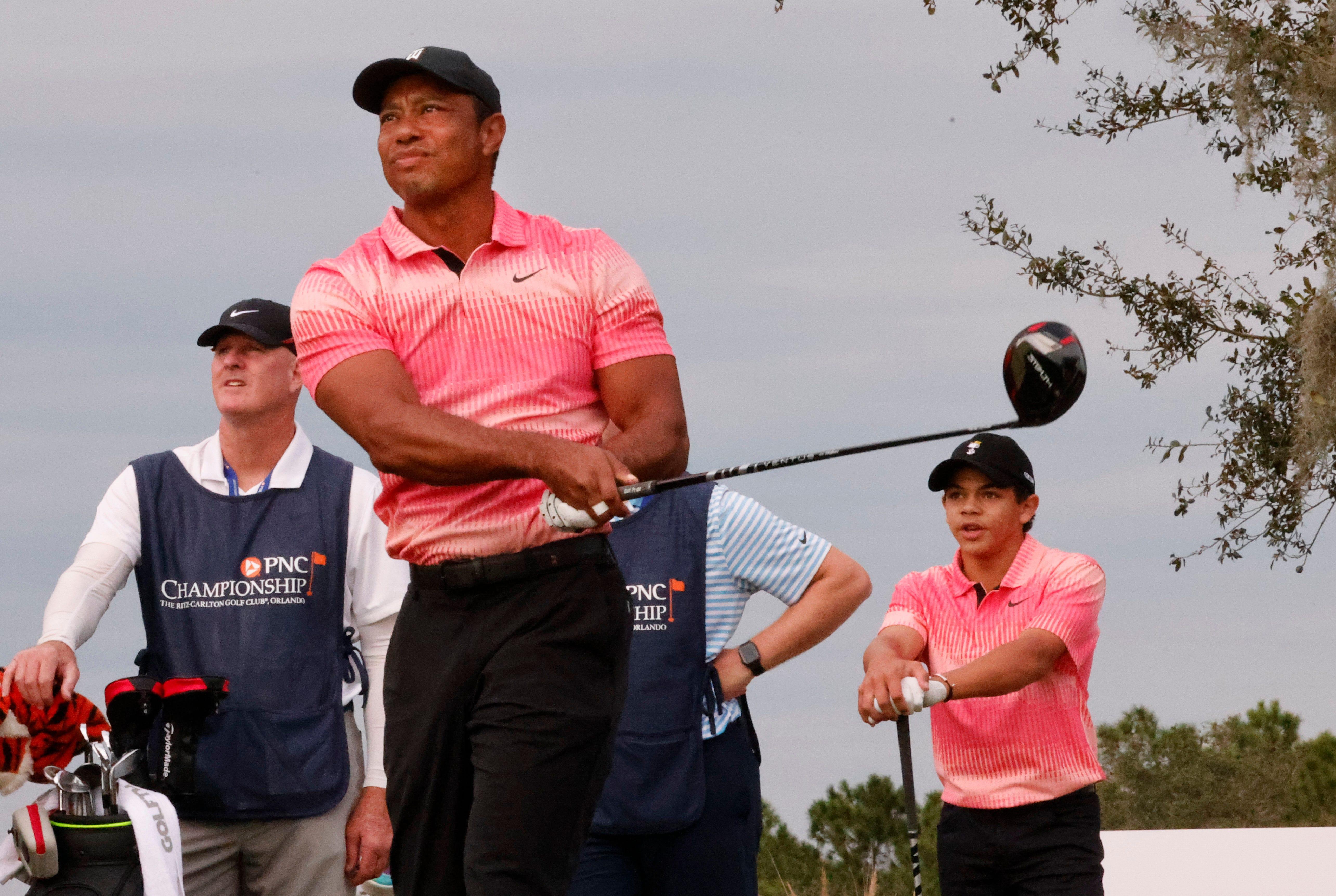 Charlie Woods (right) watches as his father Tiger Woods hits his tee shot on the tenth tee during the first round of the PNC Championship golf tournament in Orlando on Dec 17, 2022.