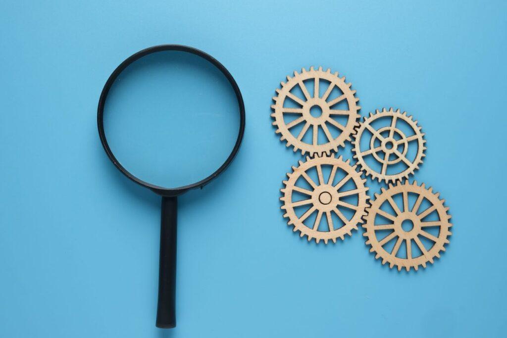 Magnifying glass and gears on blue background