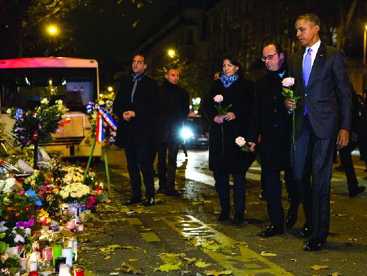 An image of Barack Obama, François Hollande, and Anne Hidalgo laying roses at a makeshift memorial.