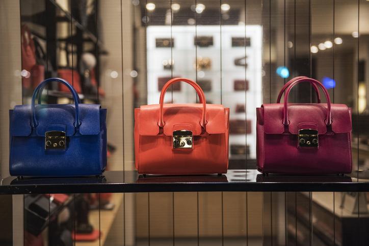 Three luxury handbags sit on a shelf in a store