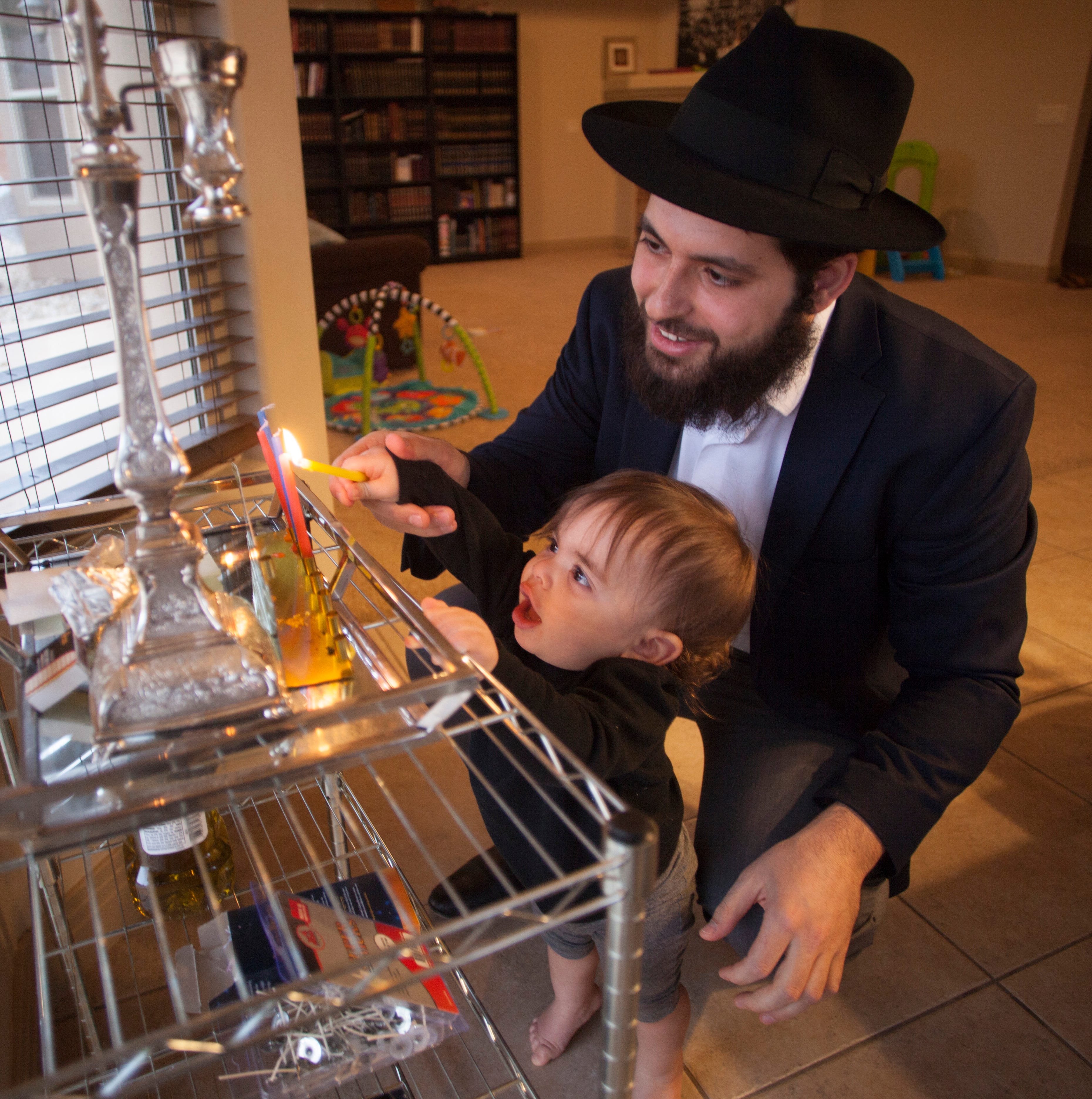 Rabbi Mendy Cohen and his son light the menorah during Hanukkah on Wednesday, Dec. 5, 2018.