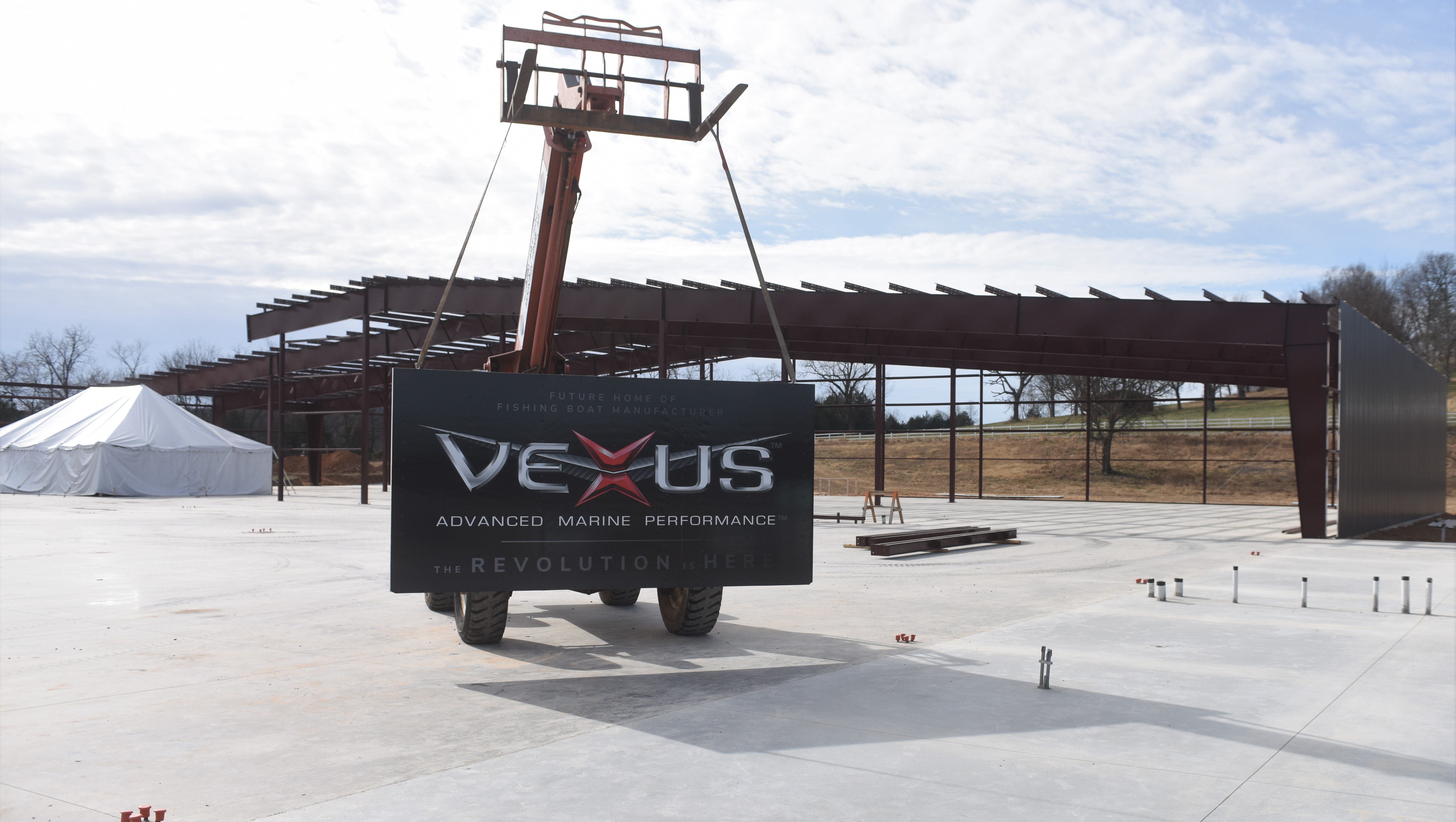 A sky lift bearing the Vexus Boats logo is parked in front of the boat manufacturer