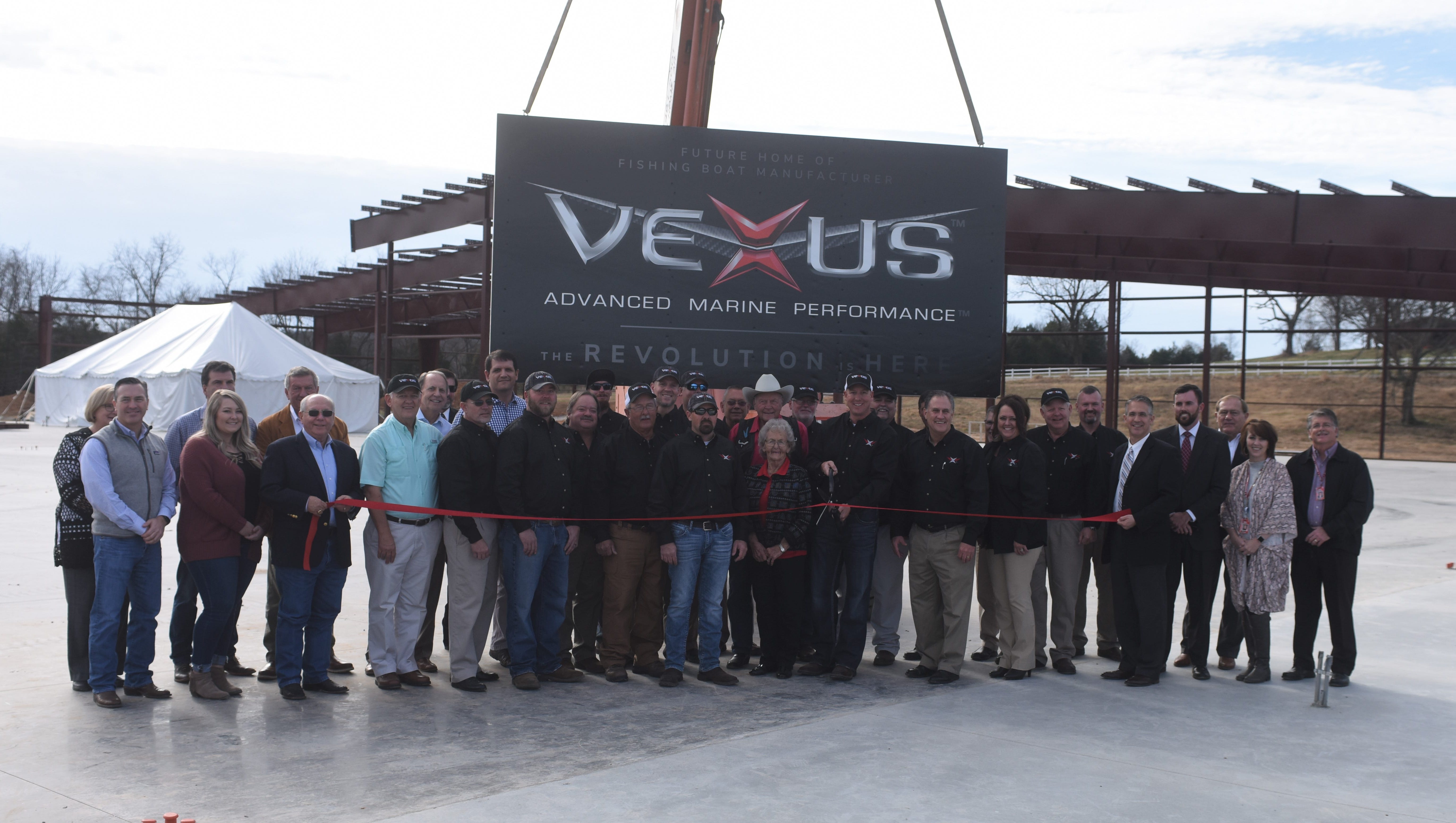 Vexus Boat employees are joined by business partners and community leaders as company president Keith Daffron cuts the ribbon on the company