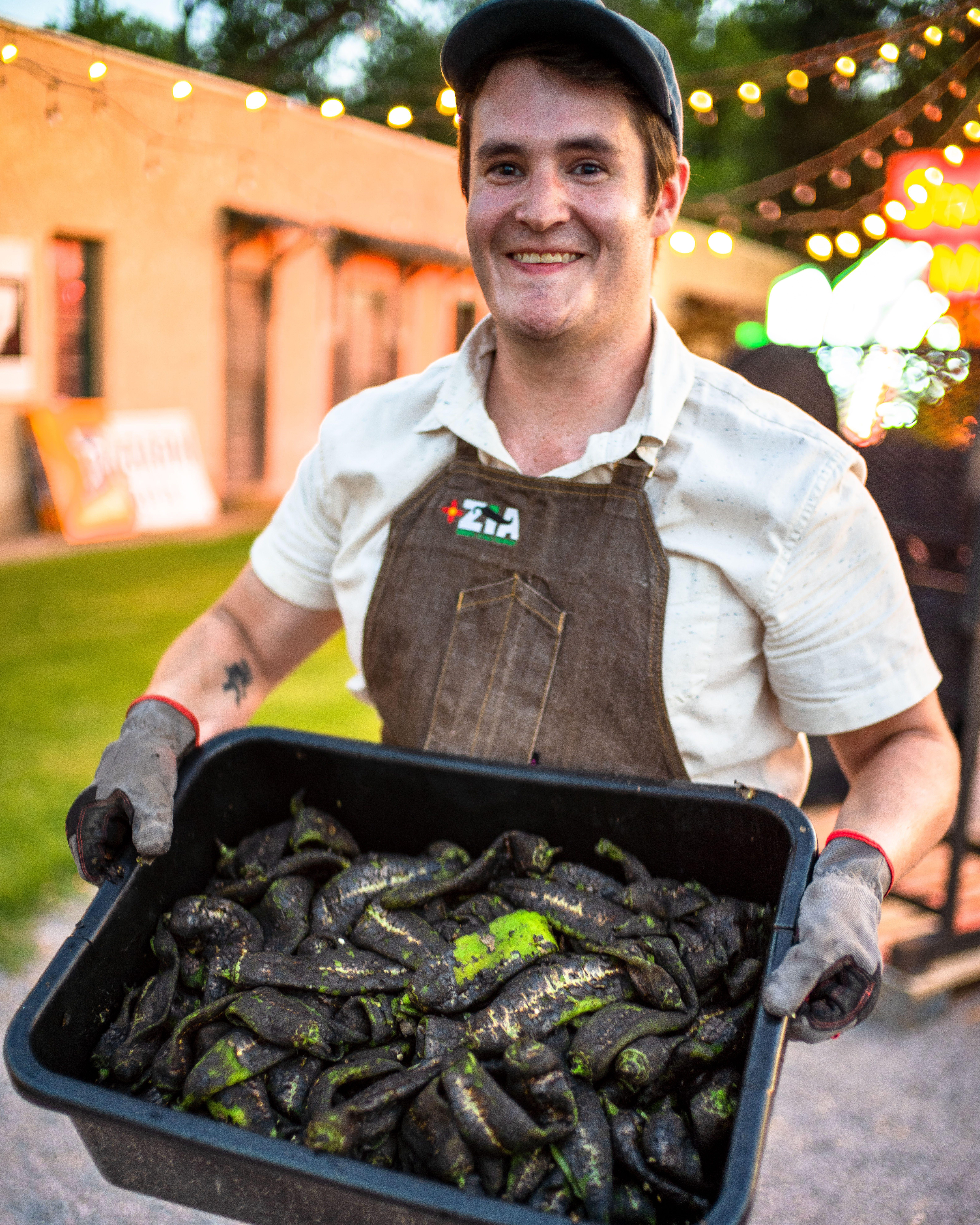 Nathaniel Cotanch, founder of the Zia Hatch Chile Company, carries a tub of freshly roasted green chile in Hatch in July 2020.