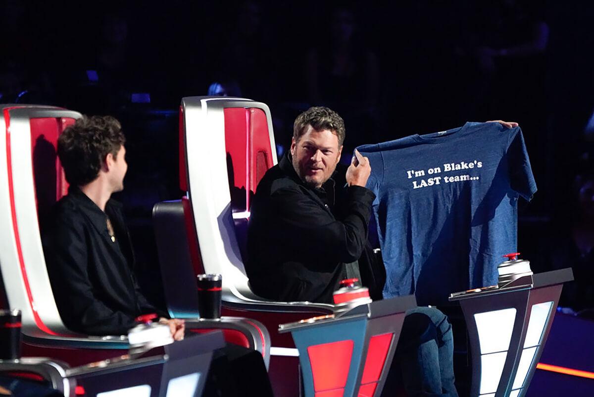 The Voice: Niall Horan looks at Blake Shelton holding up his coach gift, a blue T-shirt that reads,