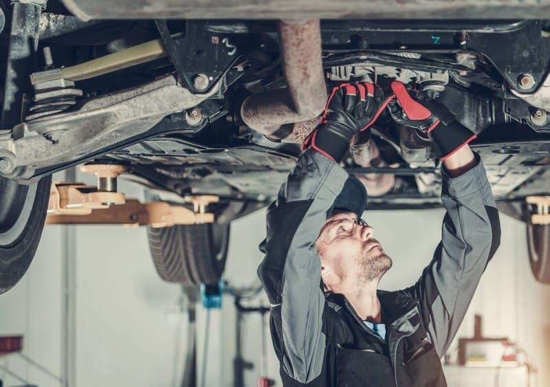 Mechanic fixing a car hoisted up on a hydraulic lift