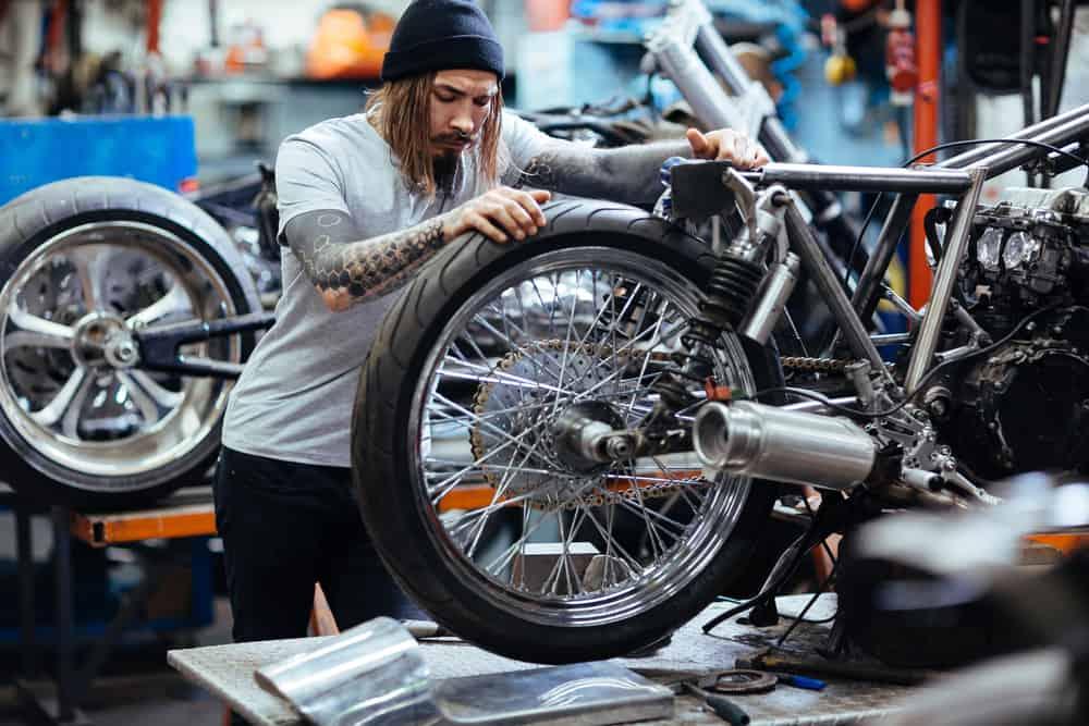 Hipster repairing wheel of motorcycle