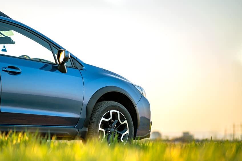 Subaru XV blue car in the field with grass with the passenger side tire visible
