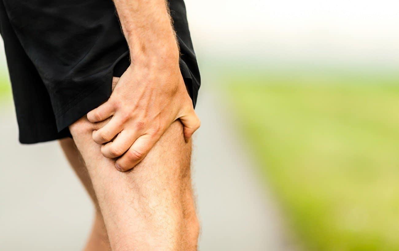 A runner holding his quad is experiencing sore quads after running.