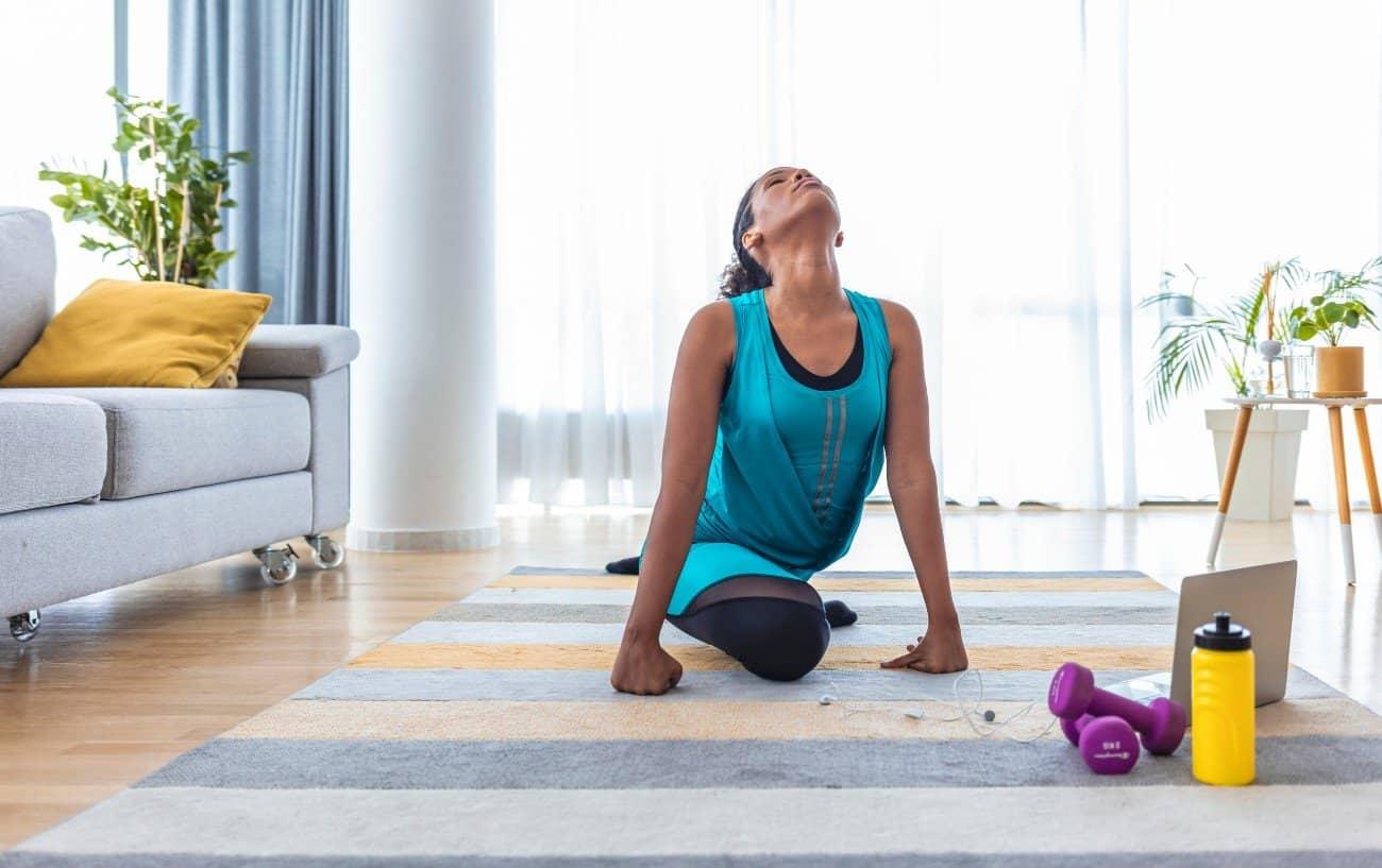 A woman doing a quad stretch in her living room.