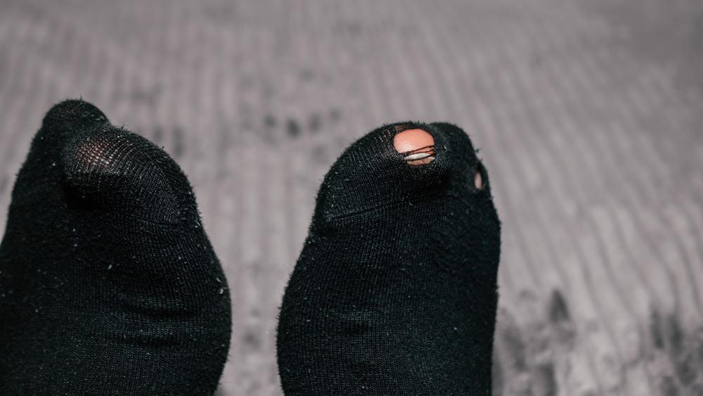 Pair of socks with hole and a finger sticking out of them