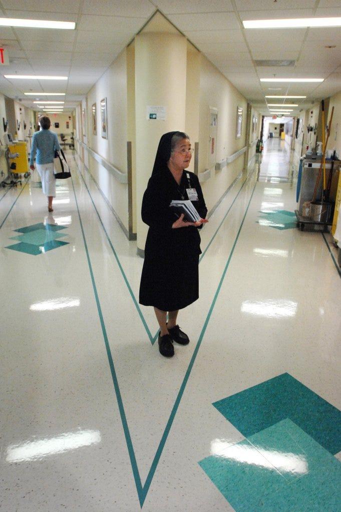 Sister Lucie Thai stops to consider her next room visit at a hallway intersection at St. Vincent
