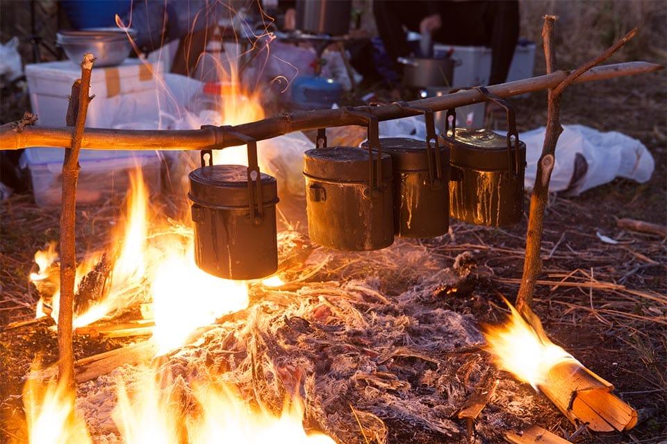 Using bamboo as firewood in campfire to heat up some meals.