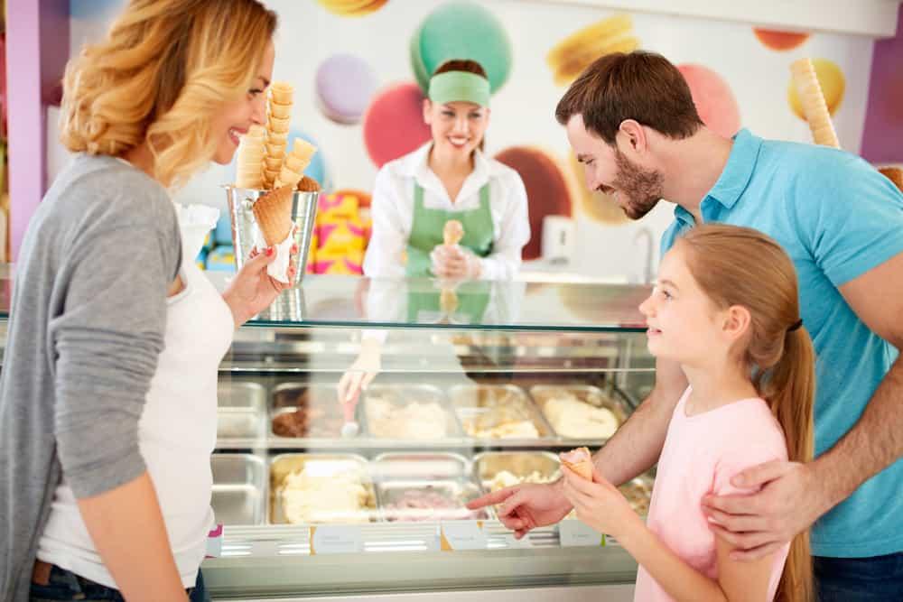 Shopkeeper in pastry shop gives ice cream to girl