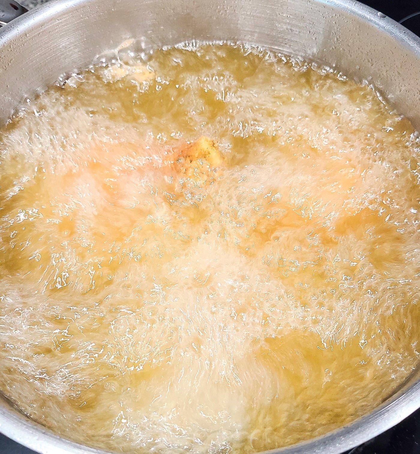 Bubbling oil frying breaded chicken pieces