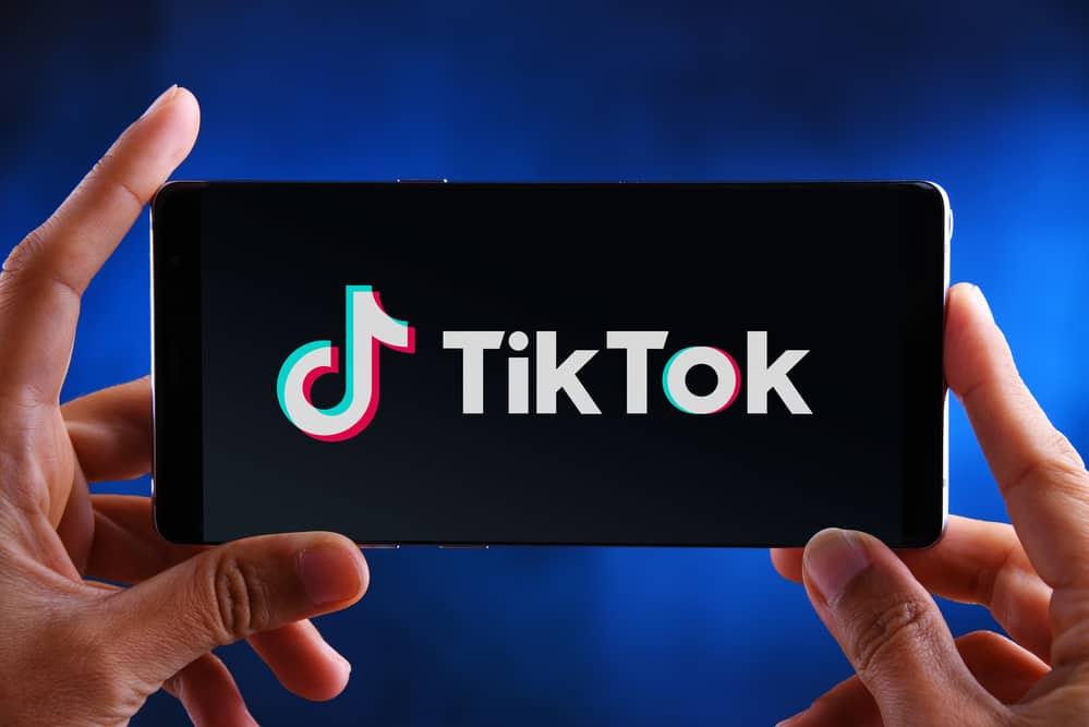 holding phone with tiktok logo