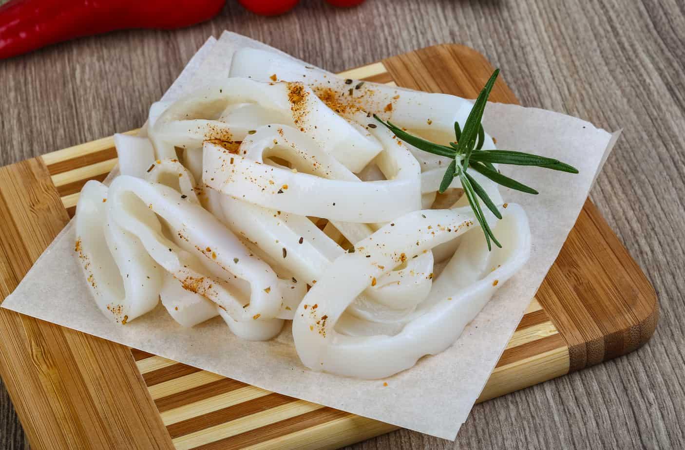 raw squid rings with herbs on a cutting board