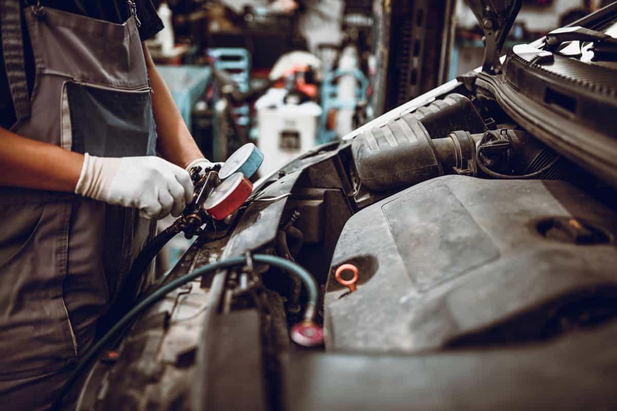 Young Mechanic Attaching Cables to Recharge Car with Freon