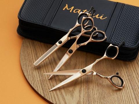 Three pairs of Matsui professional hairdresser scissors in gold and black.
