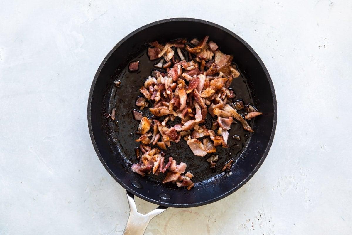 Bacon frying in a black skillet.