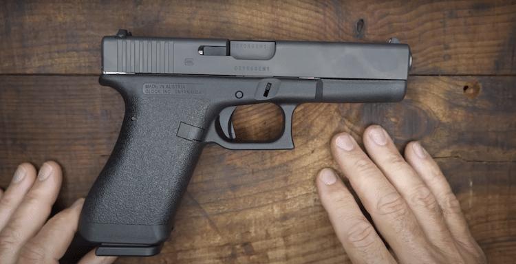 Gen 1 Glock on top of a wooden table and hands on the side