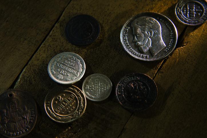 A rare variety of coins are resting on a wooden table.