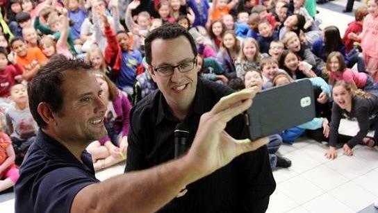 Russell Taylor (left) and Jared Fogle take a selfie in front of a group of students at a school in Arkansas. Taylor and Fogle are serving prison sentences on federal child pornography charges.