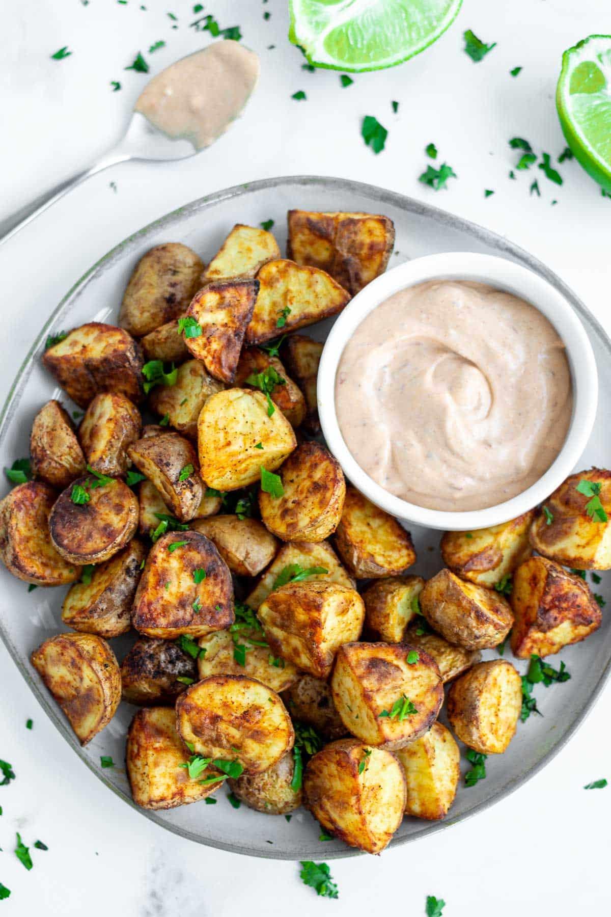 Air Fryer roast potatoes on a plate with a dipping sauce.