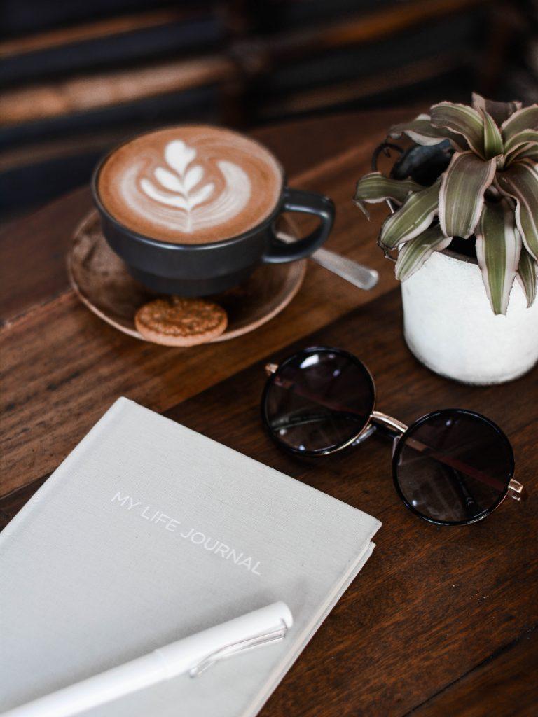 journal with coffee and sunglasses for 369 manifesting method