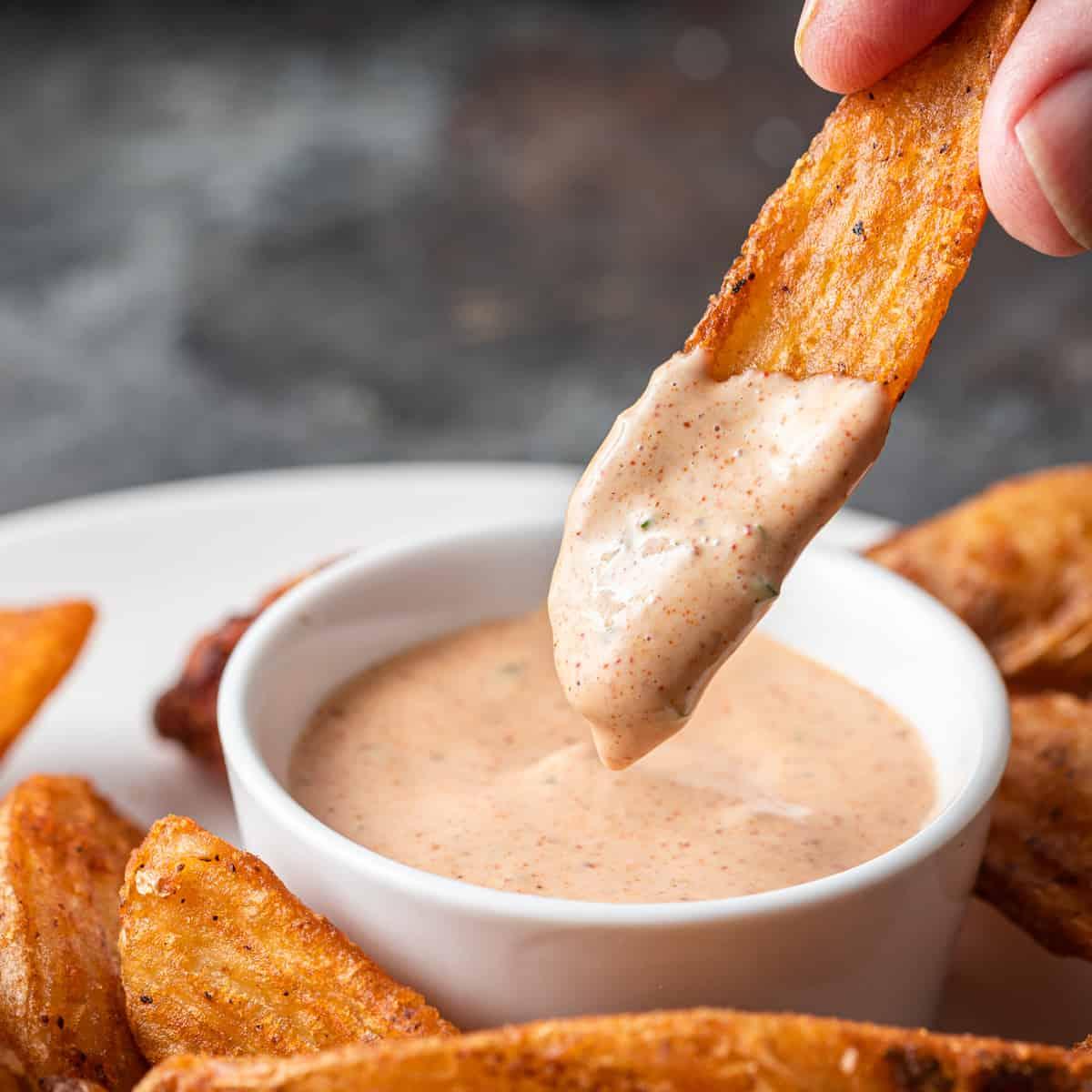 Potato wedge being dipped into Zesty Bistro Sauce