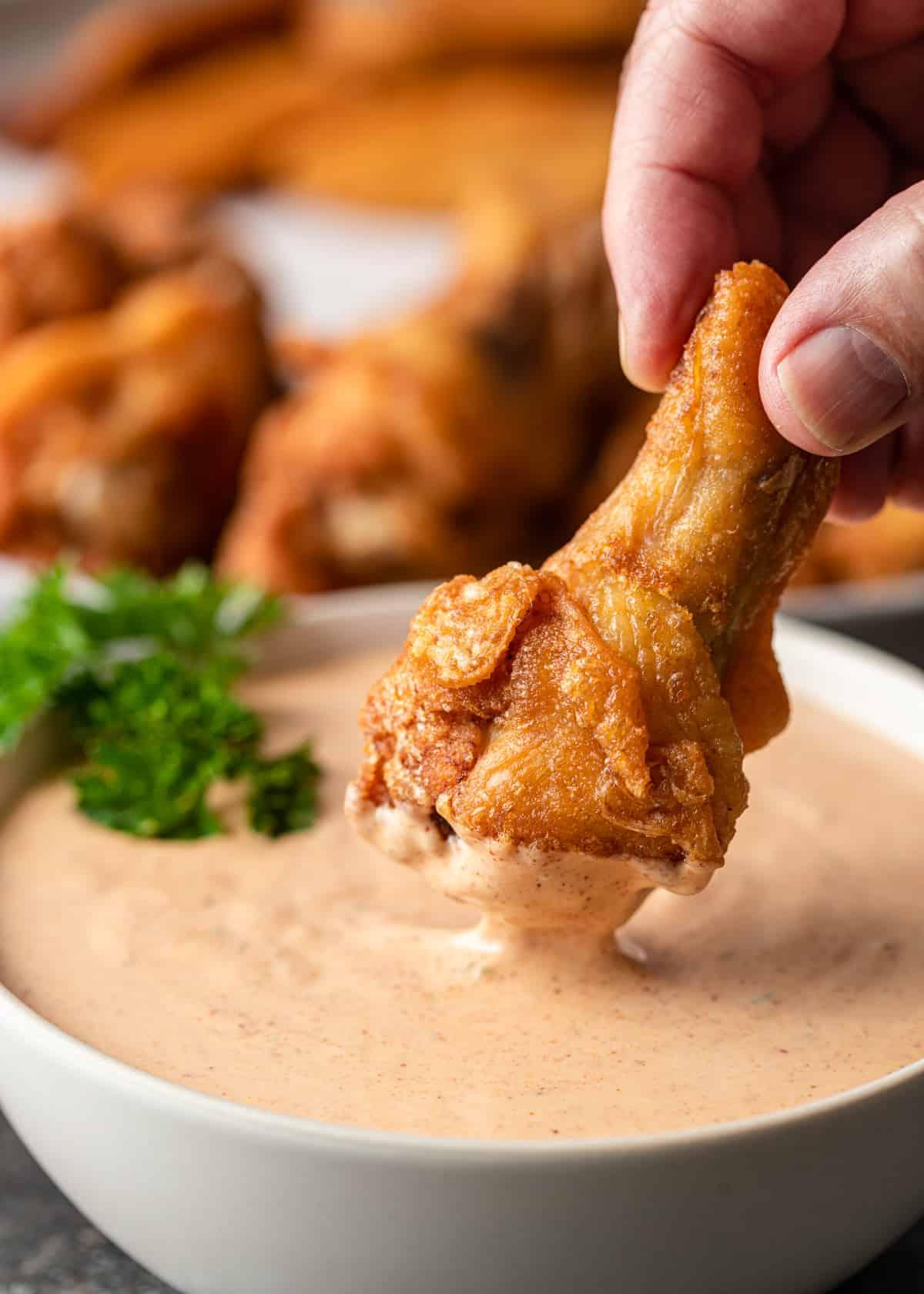 dipping chicken wings in Zesty Bistro Sauce