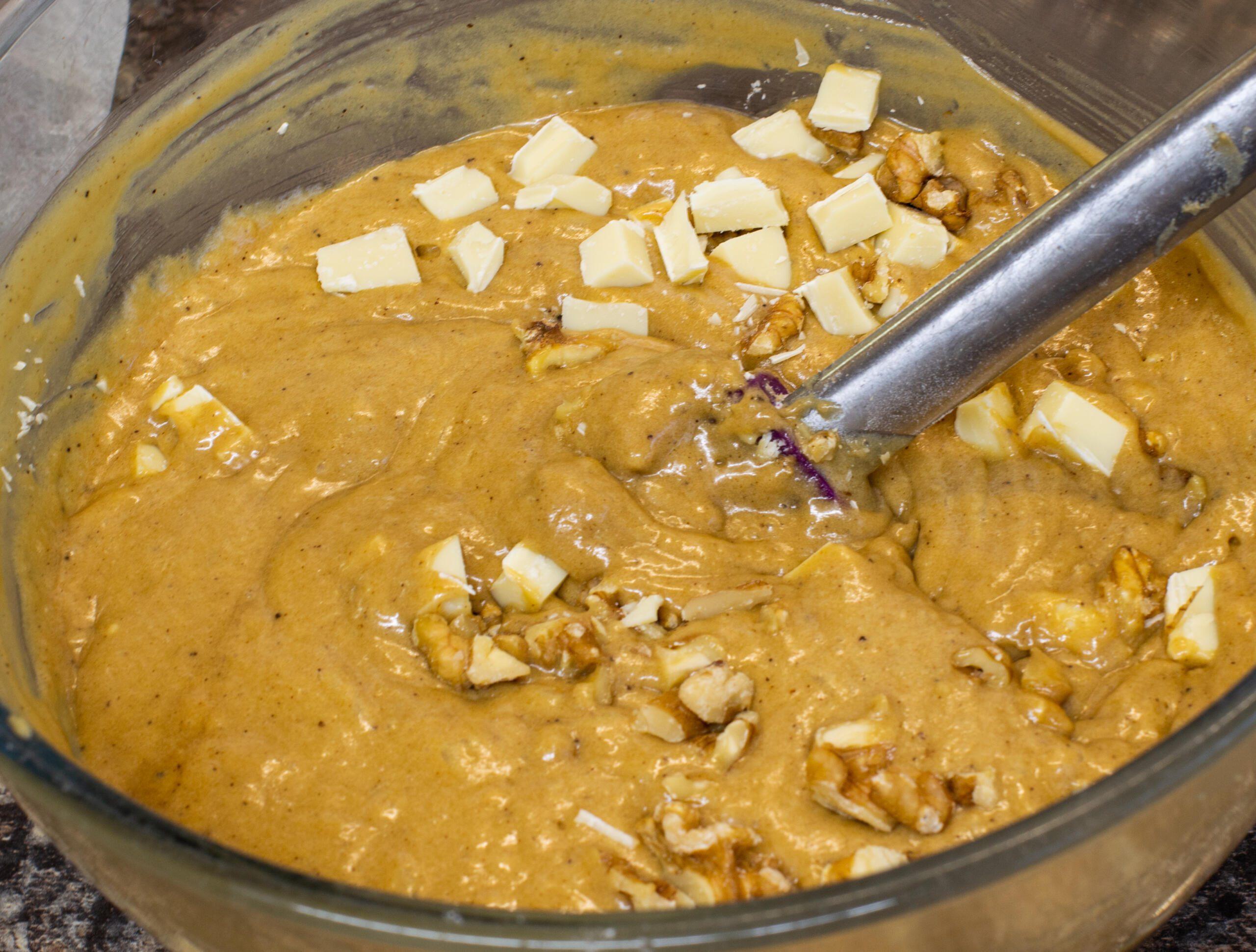 Smoothing coffee and walnut blondie batter in a tin with a purple spatula