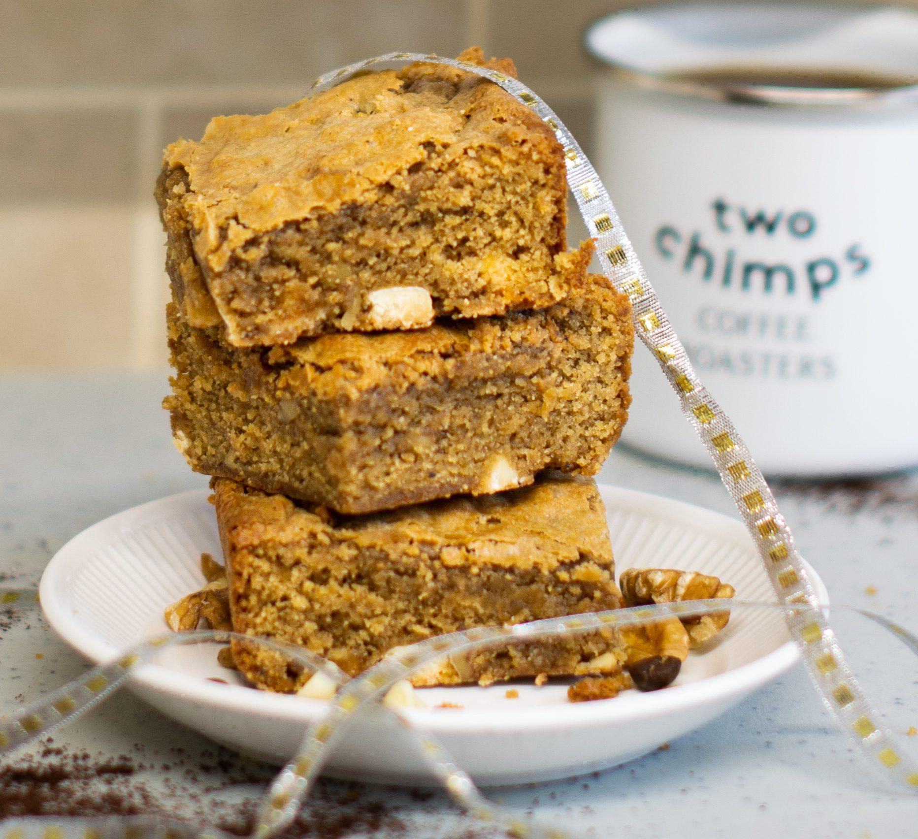 Coffee blondies on a chopping board with knife, silver ribbon, coffee beans and raspberries