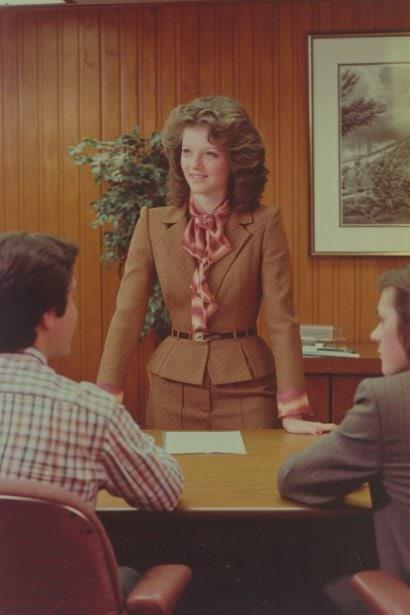 A photo capturing a young female manager, looking authoritative yet approachable, standing at the head of a small conference table. She