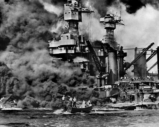 The battleship USS West Virginia settles on an even keel to the bottom of Pearl Harbor after sustaining multiple torpedo hits from Japanese planes on December 7, 1941. Rescuers in a motor launch pull a sailor from the water as smoke billows.
