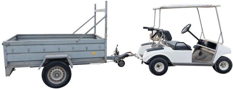 A white golf cart pullling a golf cart trailer.