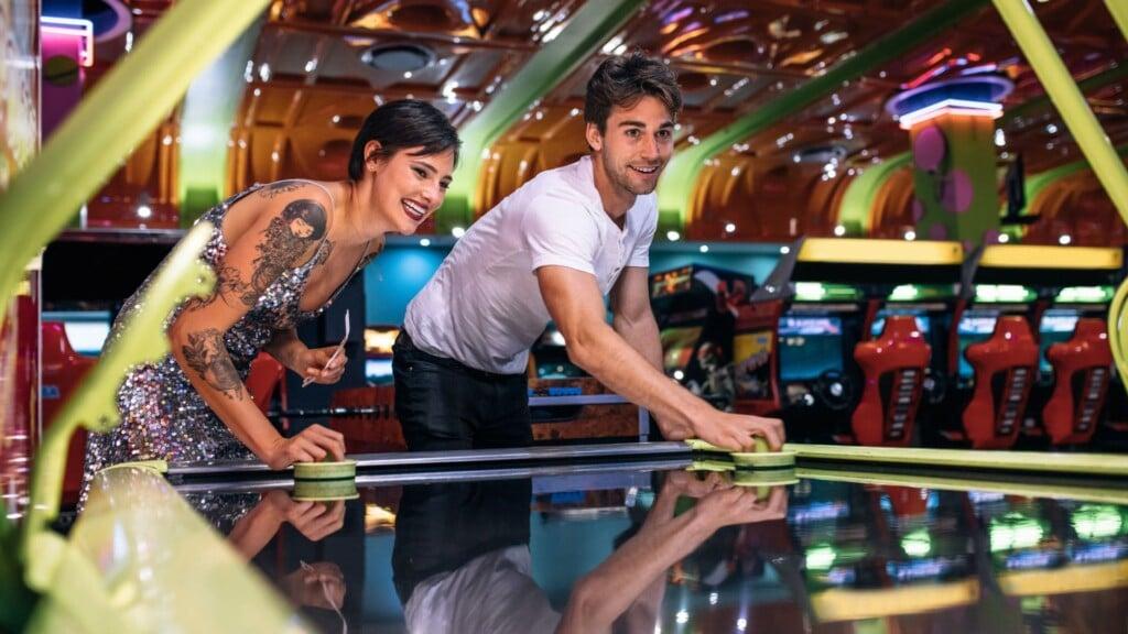 a man and a woman playing table hockey at an arcade on a rainy day