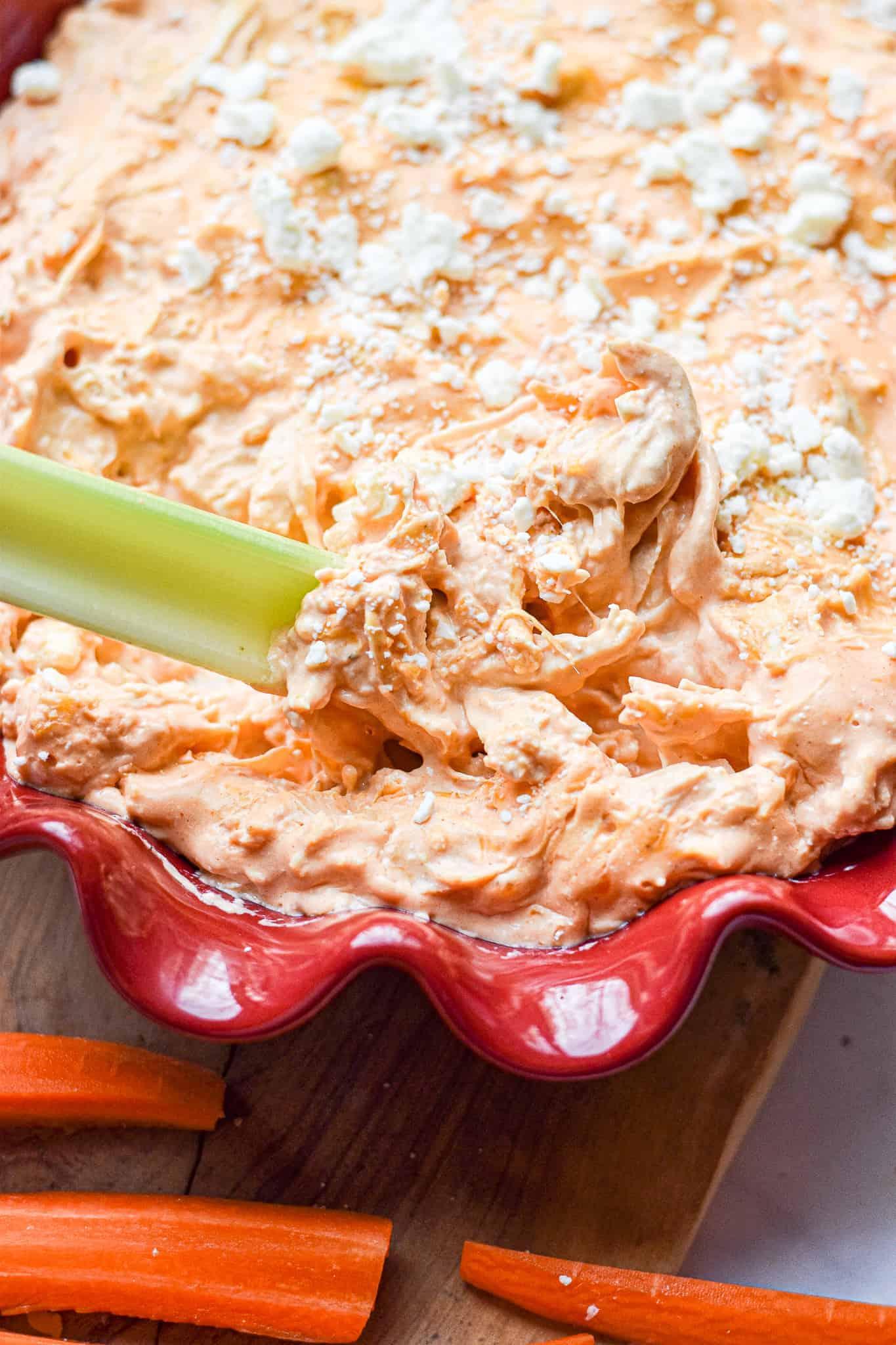 A celery stick is being dipped into the Instant Pot Buffalo Chicken Dip