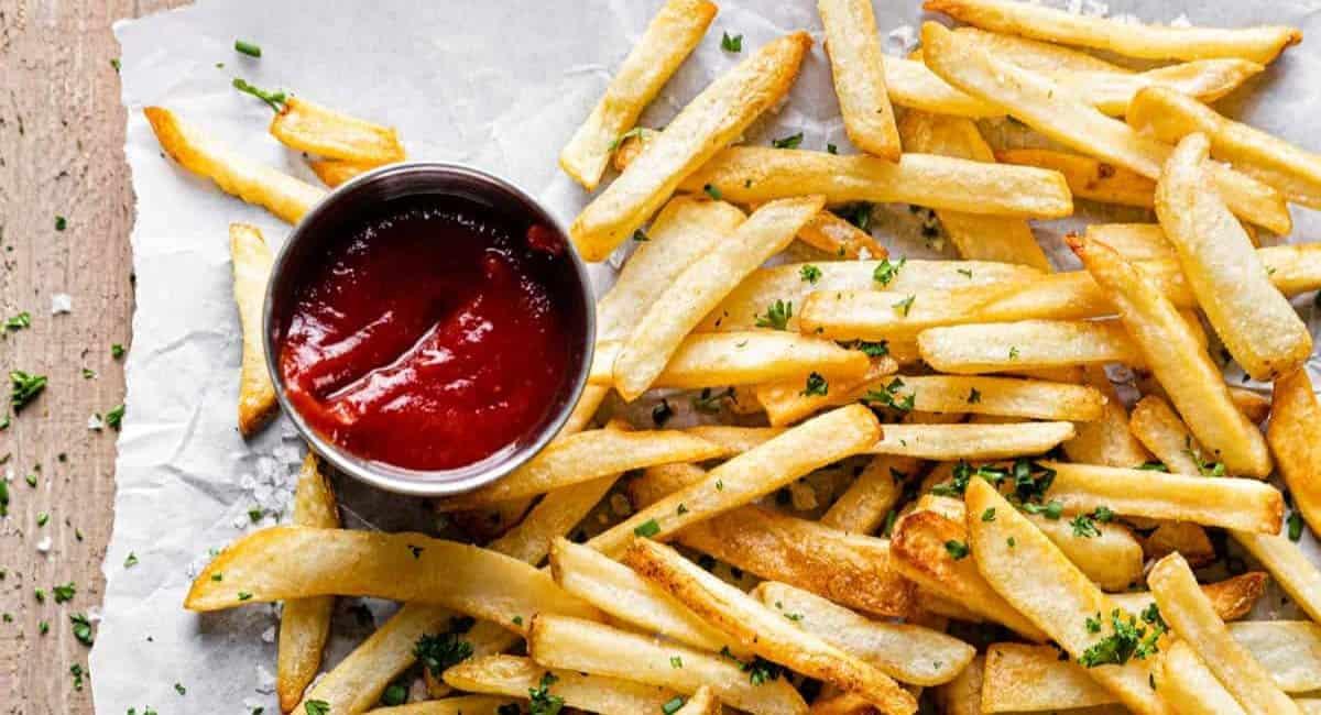 French fries on parchment paper served with ketchup as a perfect side for meatball subs.
