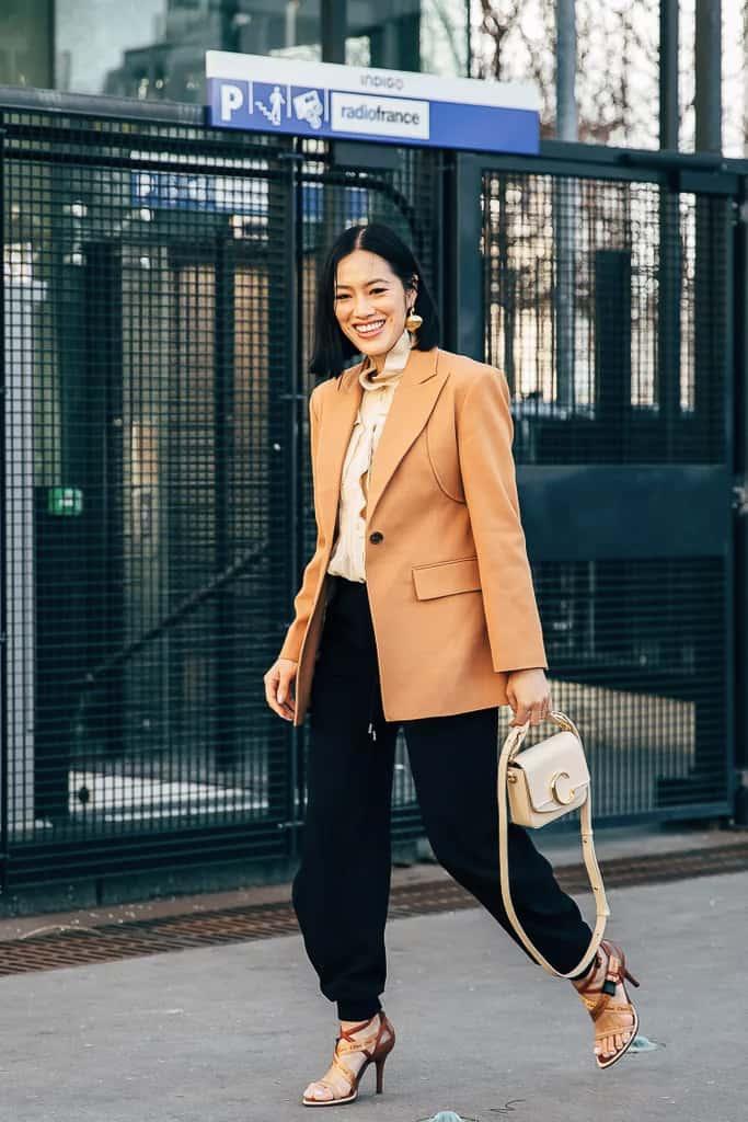 woman wearing an oversized tan blazer with silk black joggers and brown sandal heels