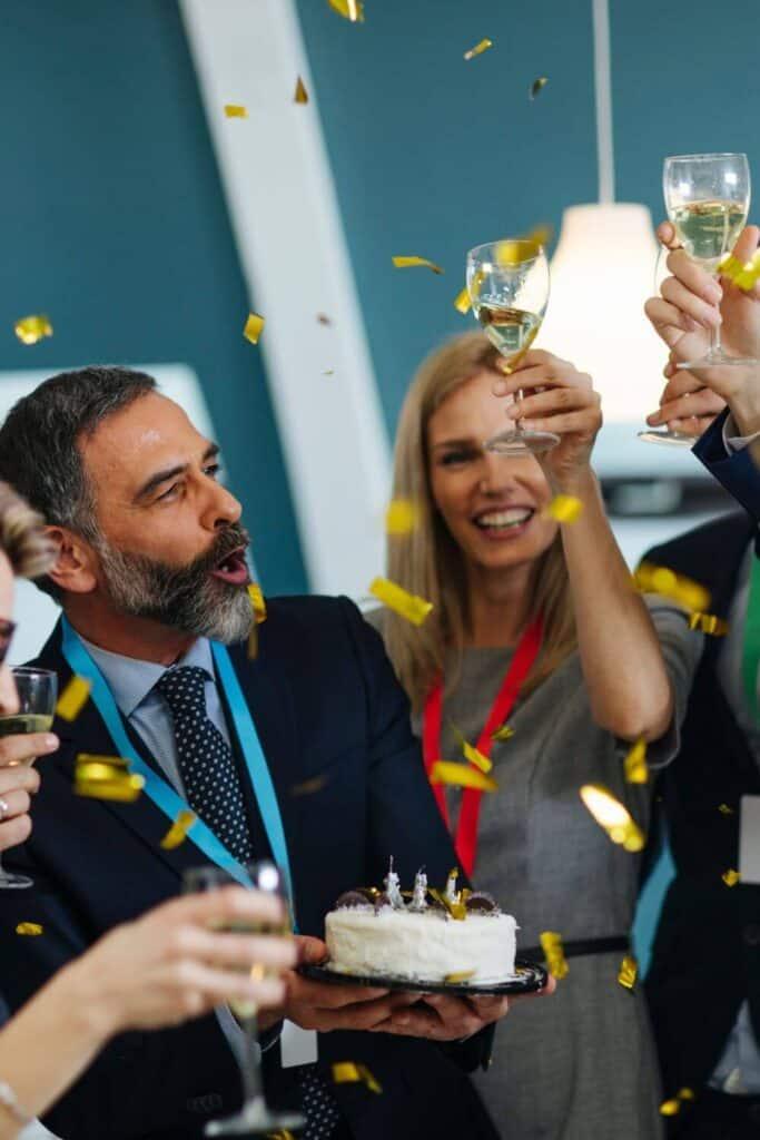 man lifting glass of beer and smilinw with happy retirement banner behind him