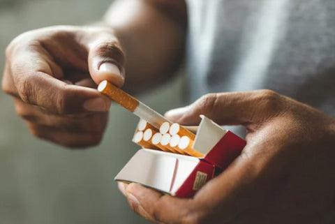 a person pulling out a cigarette from the pack