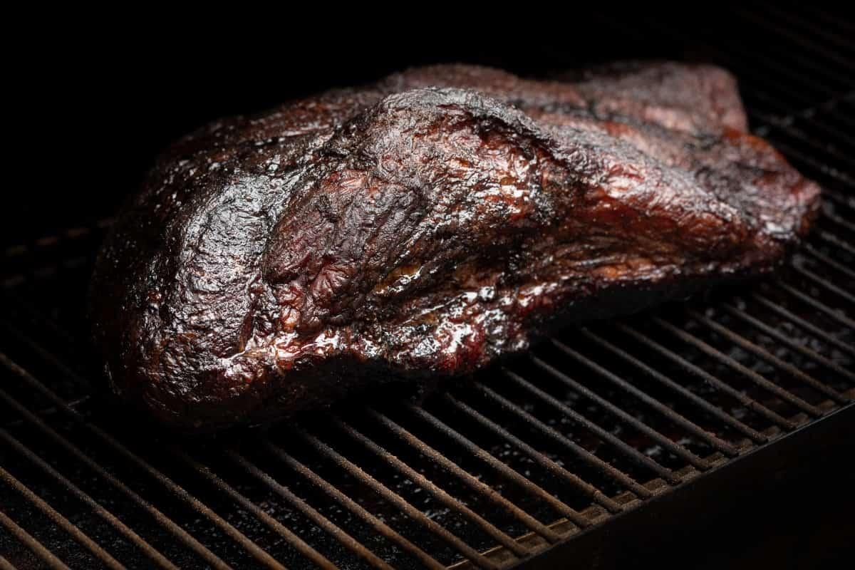 A brisket with bark set on grill gra.