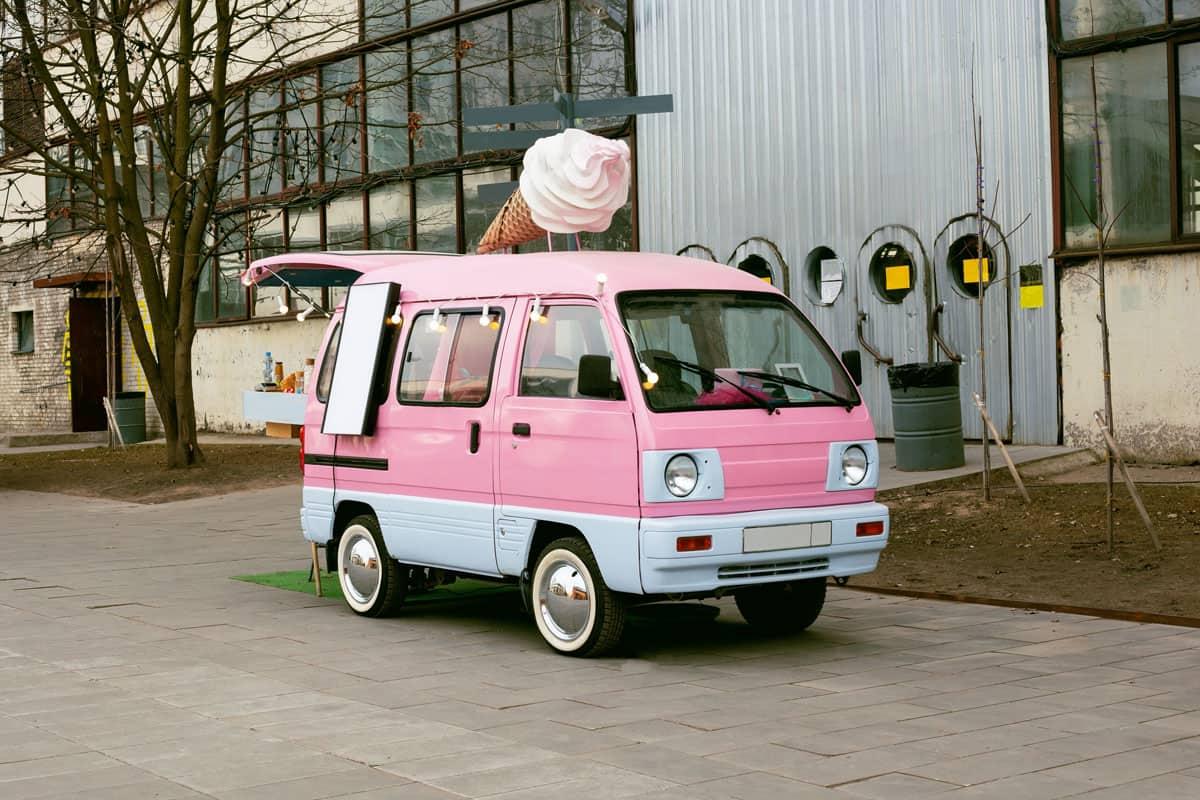 small pibk and white ice cream truck along the road