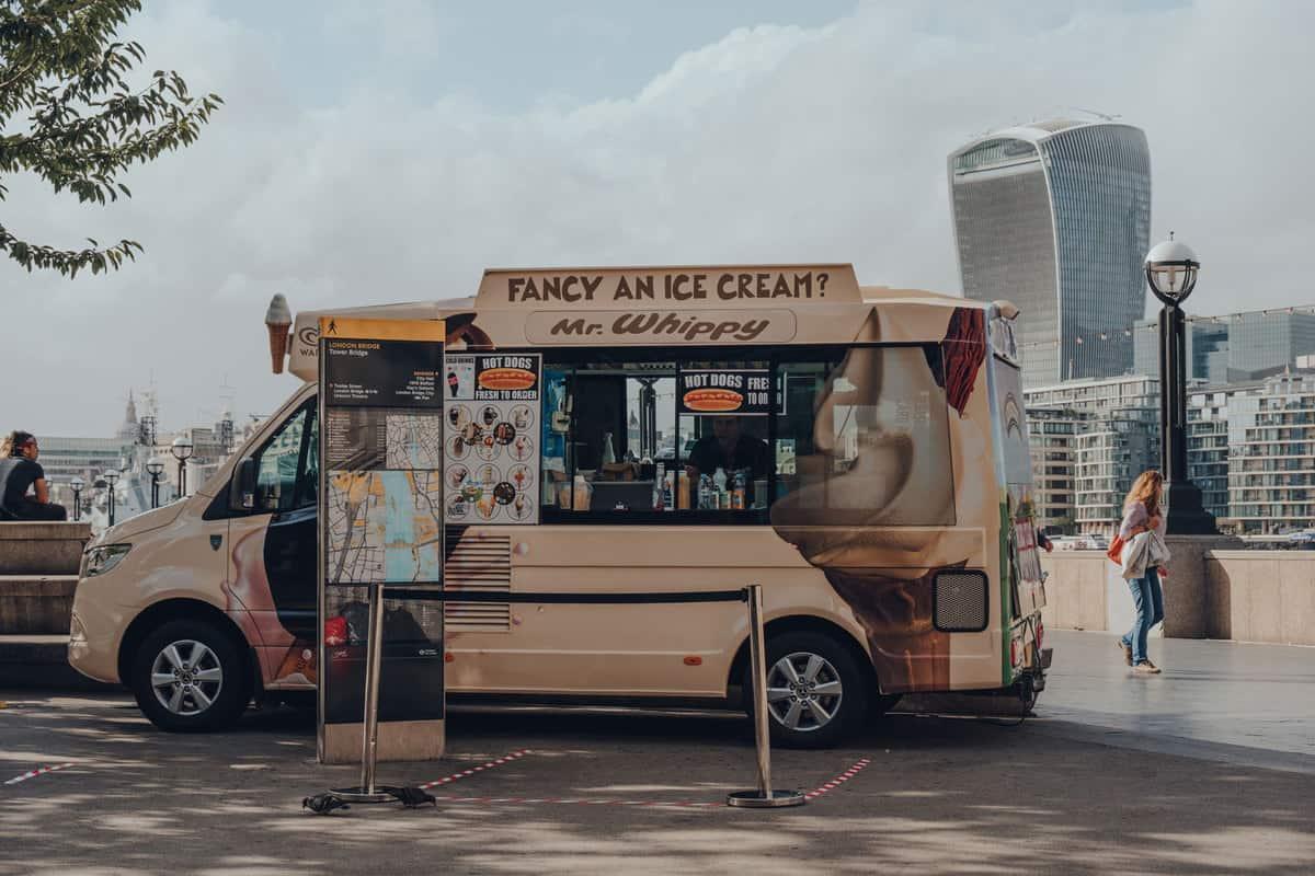 A brown colored ice cream truck parked on the side of a park, When Do Ice Cream Trucks Come? [Here