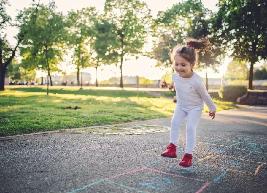 little girl playing hopscotch