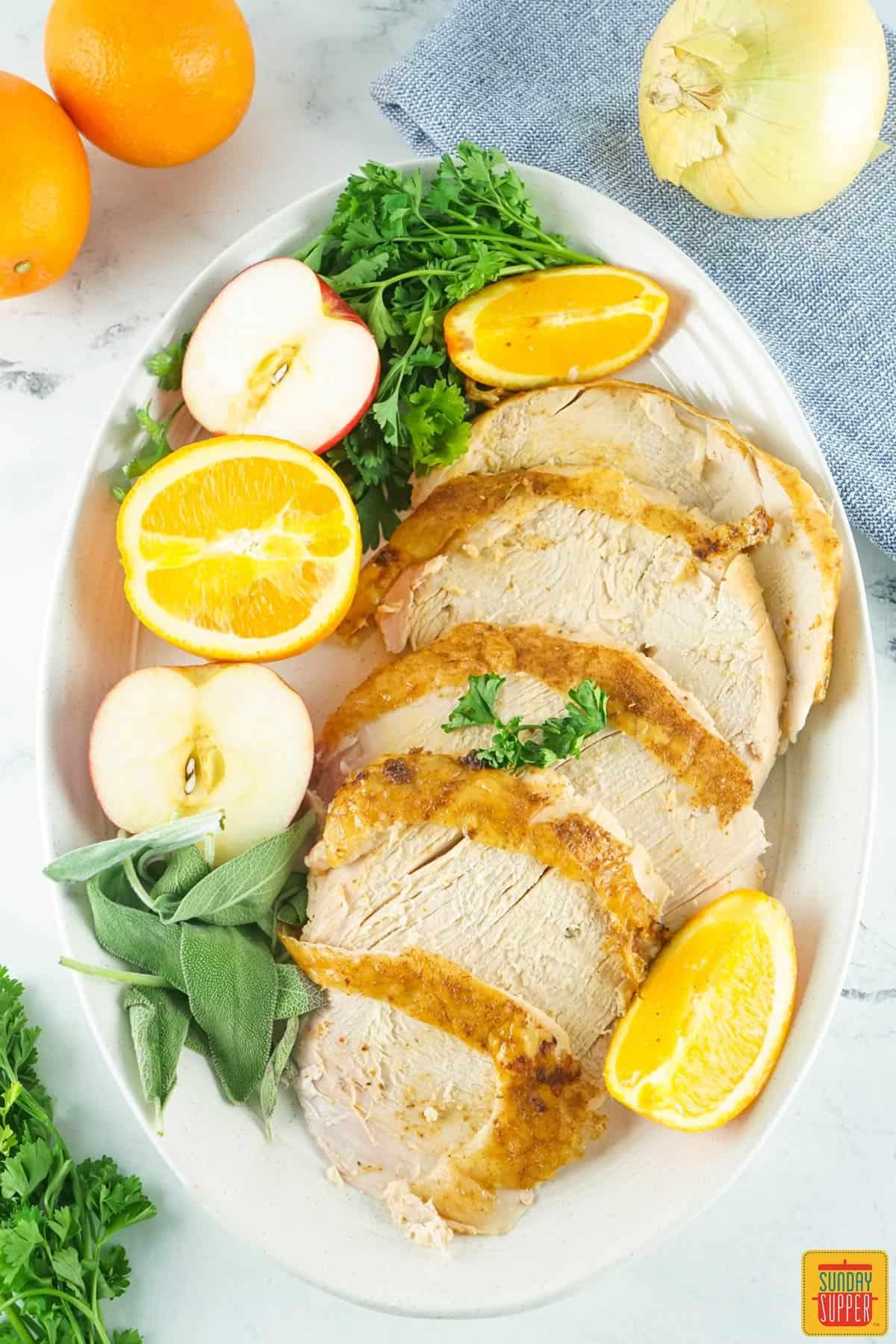 smoked turkey sliced on a platter with citrus and herbs